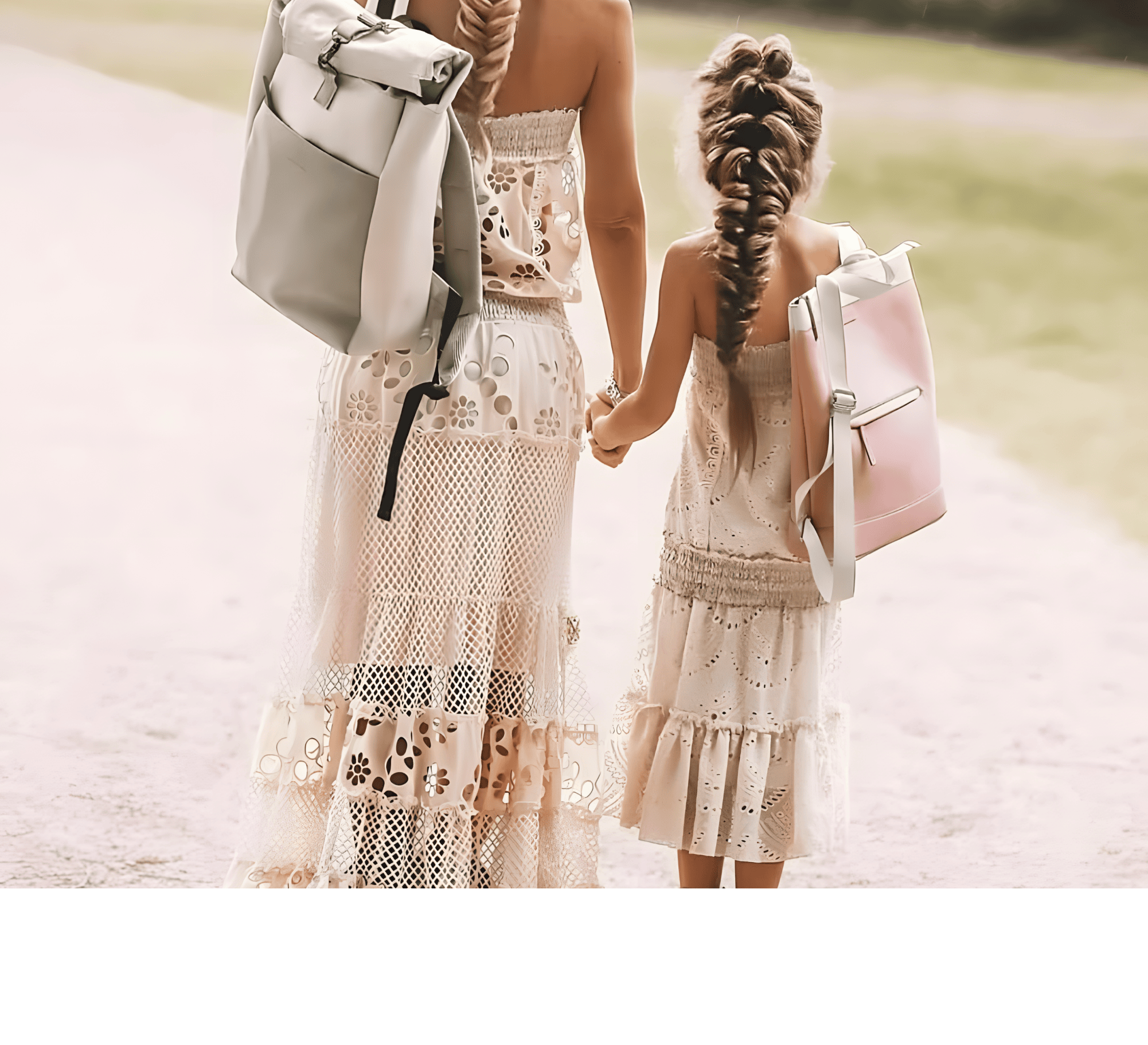 Mother and daughter walking hand in hand wearing matching cream lace dresses and stylish backpacks